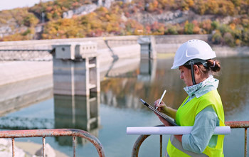 person with hard hat working at a dam